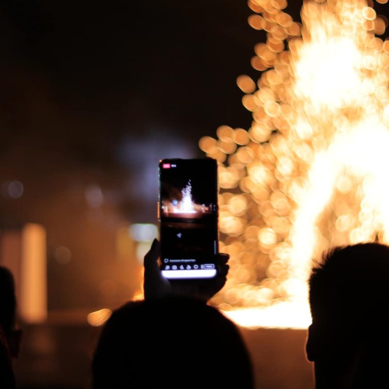 person taking photo of fire during night time