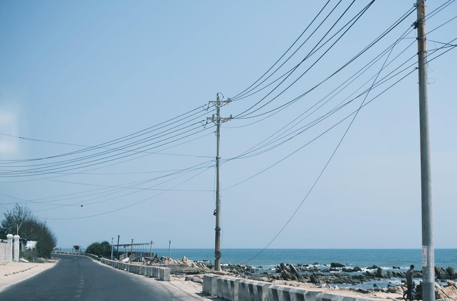 Road alongside the ocean with power lines